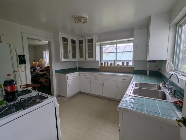 kitchen featuring white cabinetry, sink, white appliances, and tile counters