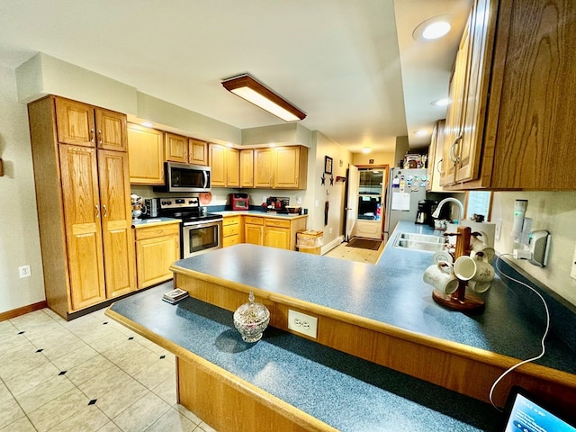 kitchen with light tile patterned flooring, stainless steel appliances, kitchen peninsula, and sink