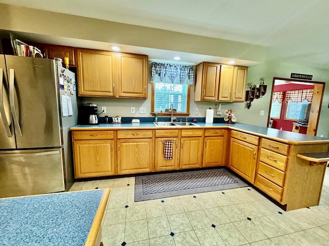 kitchen featuring kitchen peninsula, light tile patterned floors, stainless steel refrigerator, and sink