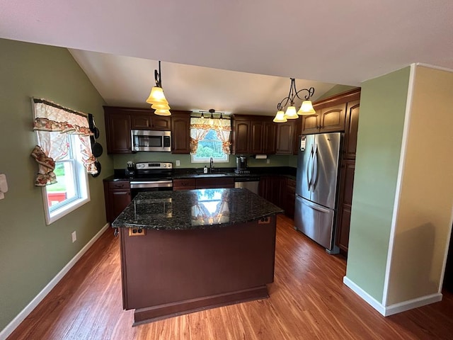 kitchen with appliances with stainless steel finishes, a center island, sink, and hanging light fixtures