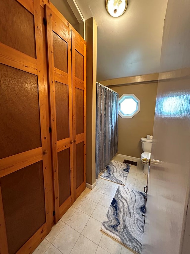 bathroom featuring tile patterned flooring, curtained shower, and toilet