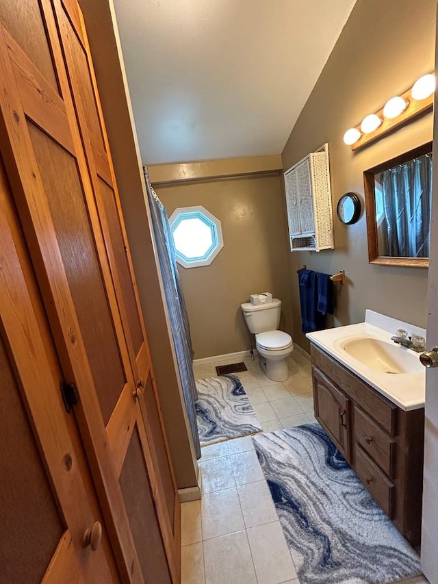 bathroom featuring tile patterned flooring, vanity, lofted ceiling, and toilet