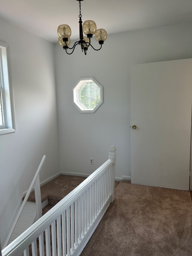 staircase with an inviting chandelier and carpet