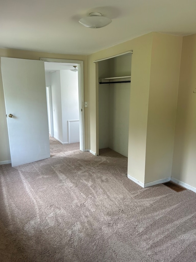 unfurnished bedroom with light colored carpet and a closet