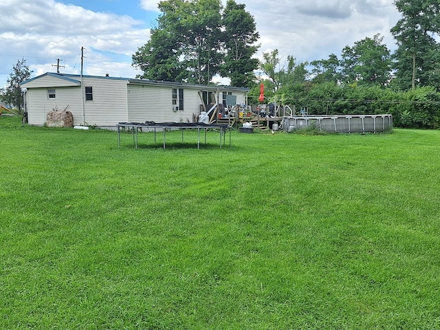 view of yard with a fenced in pool and a trampoline