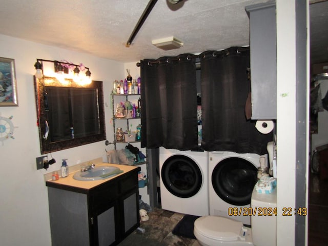 bathroom featuring vanity, a textured ceiling, washer and clothes dryer, and toilet