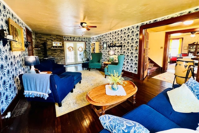 living room with dark wood-type flooring, a wood stove, french doors, and a wealth of natural light