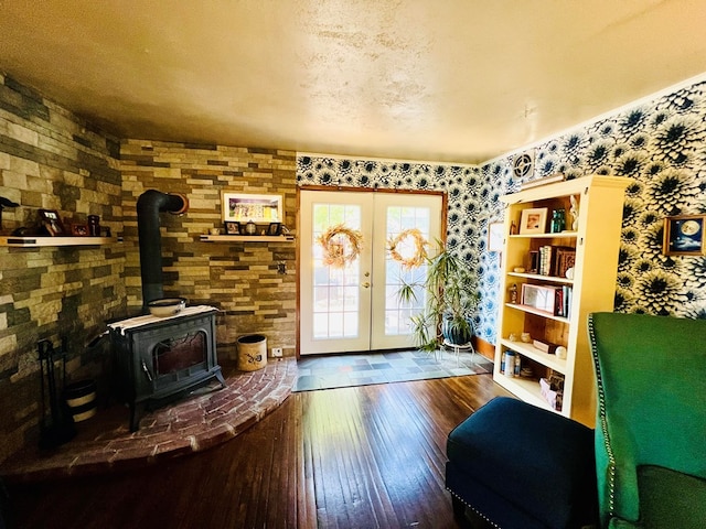 interior space featuring hardwood / wood-style flooring, a wood stove, french doors, and a textured ceiling