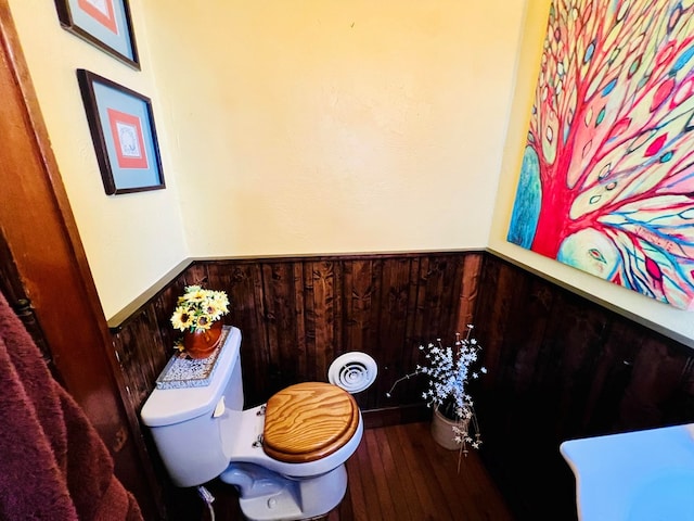 bathroom featuring wooden walls and toilet