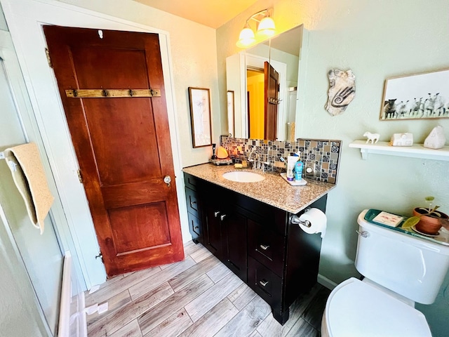 bathroom featuring backsplash, vanity, hardwood / wood-style floors, and toilet