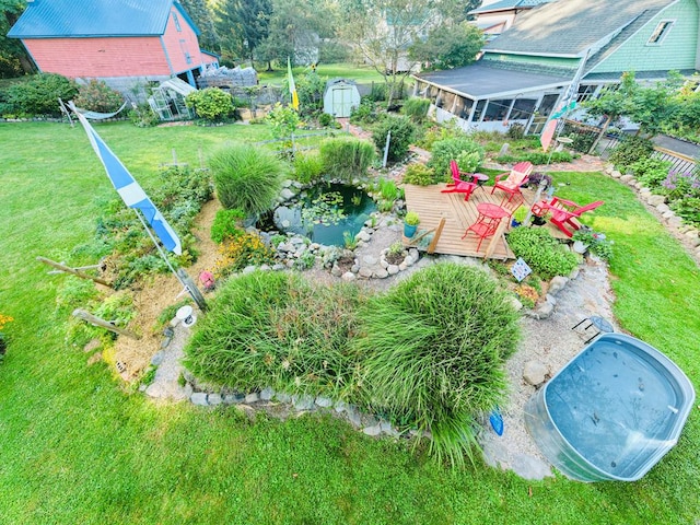 bird's eye view featuring a deck, a sunroom, a lawn, and a storage shed