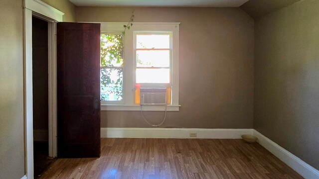 empty room with hardwood / wood-style flooring, cooling unit, and lofted ceiling