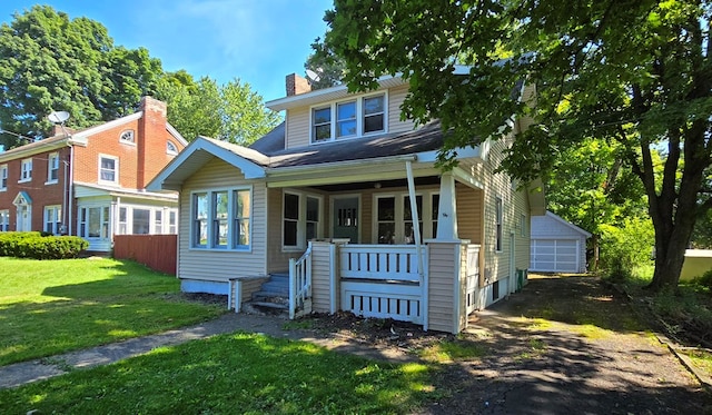 view of front facade with an outbuilding, a porch, a garage, and a front lawn