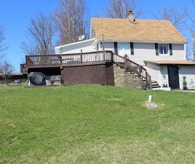 rear view of house with a wooden deck and a lawn