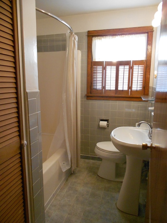 bathroom featuring tile walls, shower / bath combination with curtain, and toilet