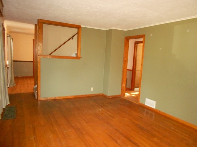 empty room featuring wood-type flooring and ornamental molding