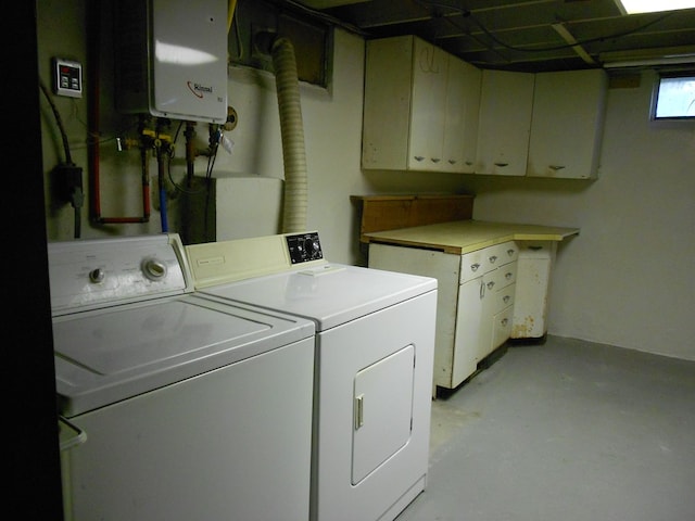 washroom featuring cabinets, water heater, and washer and clothes dryer