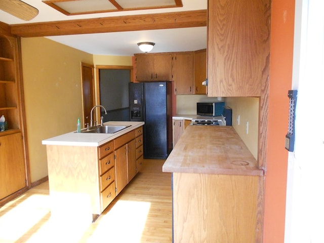 kitchen featuring sink, a kitchen island, wood counters, light hardwood / wood-style flooring, and black refrigerator