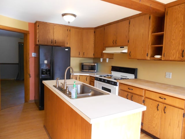 kitchen with gas range gas stove, sink, light wood-type flooring, and an island with sink