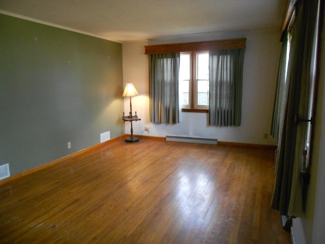 empty room featuring baseboard heating and wood-type flooring