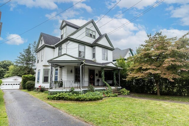 view of front of property featuring an outbuilding, a garage, a front yard, and a porch