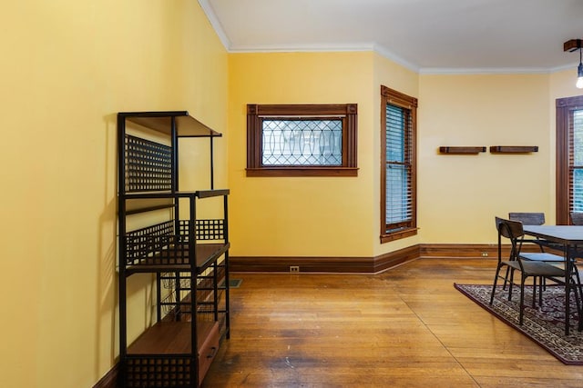 corridor featuring a healthy amount of sunlight, ornamental molding, and hardwood / wood-style floors