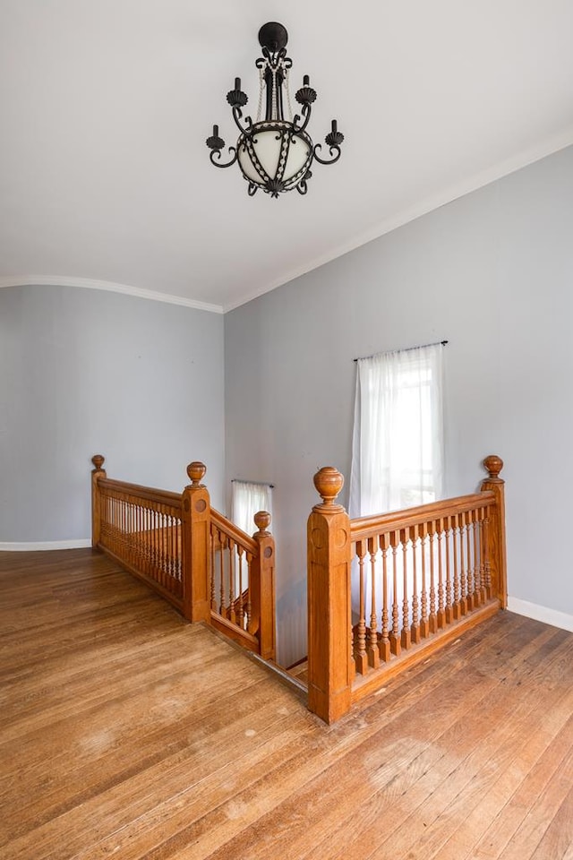 staircase featuring crown molding, a chandelier, and hardwood / wood-style floors