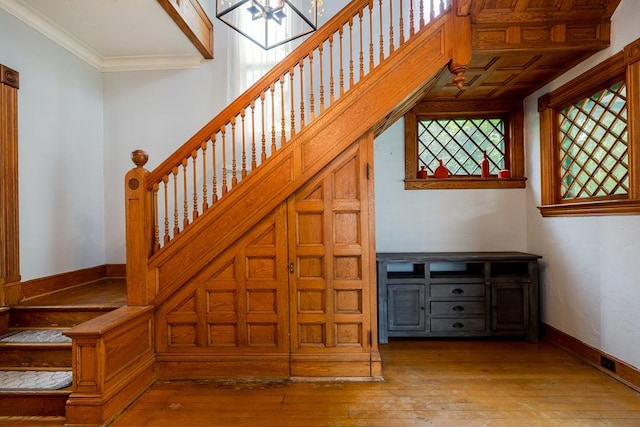 stairs with crown molding and hardwood / wood-style flooring