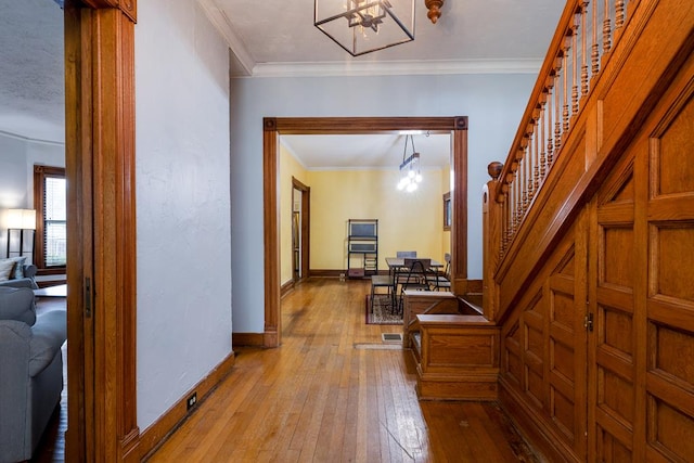 hall with ornamental molding, a chandelier, and light hardwood / wood-style flooring