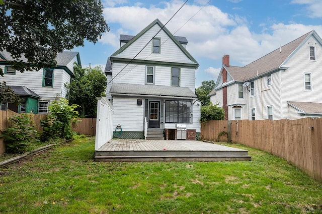 back of property featuring a deck and a lawn