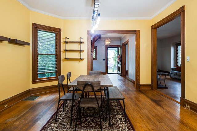 dining room featuring dark hardwood / wood-style flooring, ornamental molding, and a chandelier