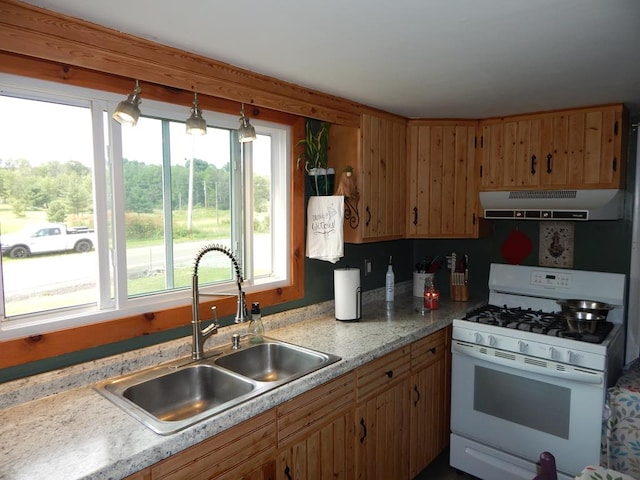 kitchen with pendant lighting, white gas range oven, and sink