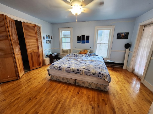 bedroom featuring light wood-type flooring, ceiling fan, cooling unit, and multiple windows