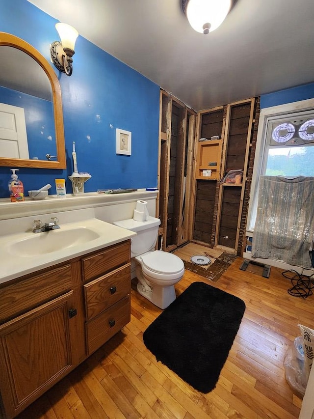 bathroom with toilet, vanity, and hardwood / wood-style floors