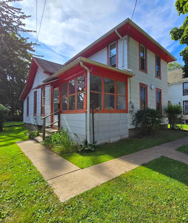 view of side of home featuring a sunroom and a yard