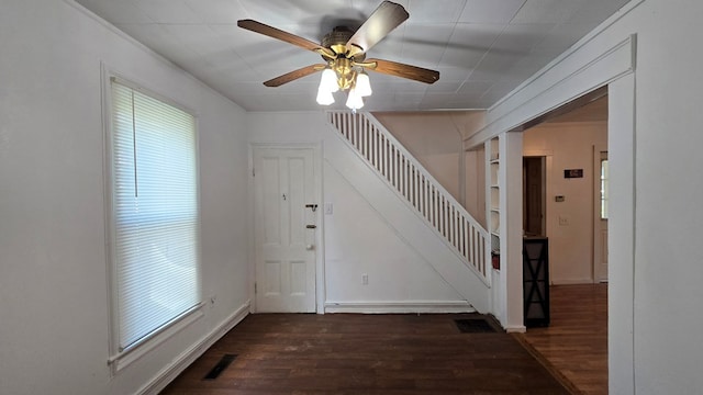 entryway featuring ceiling fan, ornamental molding, and dark wood-type flooring