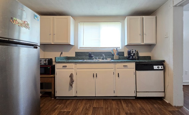 kitchen with sink, dark wood-type flooring, stainless steel fridge, white dishwasher, and white cabinets