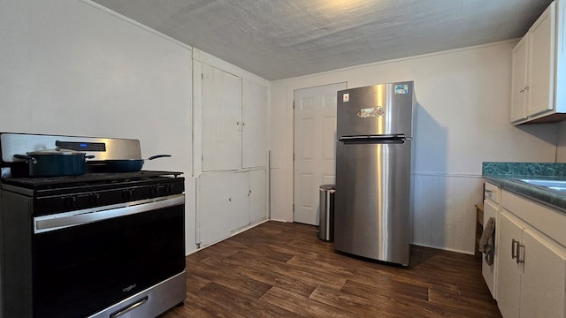 kitchen featuring appliances with stainless steel finishes, dark hardwood / wood-style flooring, a textured ceiling, and white cabinetry