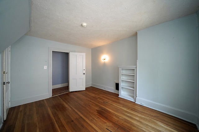 additional living space featuring a textured ceiling and dark hardwood / wood-style floors