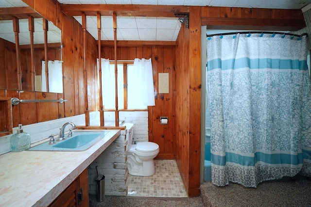 bathroom with toilet, vanity, wooden walls, and curtained shower