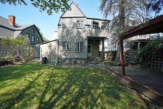 rear view of house with a wooden deck and a lawn