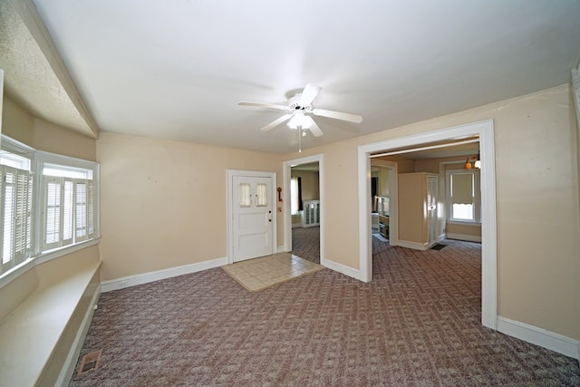 carpeted spare room featuring a wealth of natural light and ceiling fan