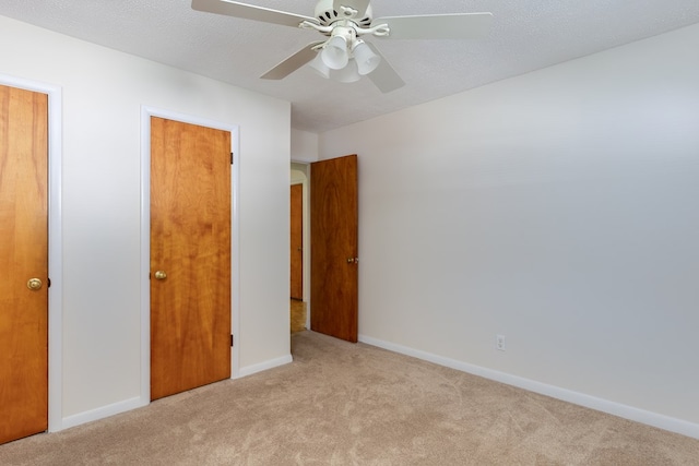 unfurnished bedroom featuring ceiling fan, light colored carpet, and a textured ceiling