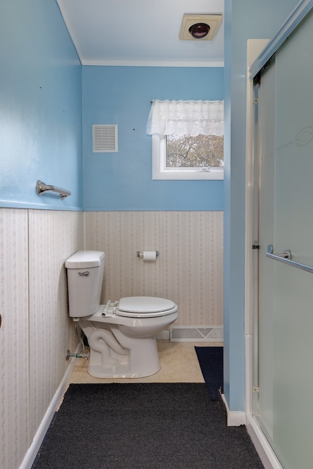 bathroom featuring toilet and a shower with door