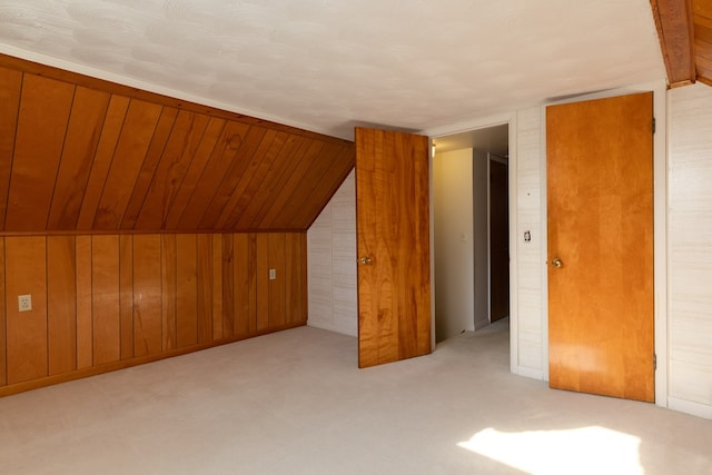 bonus room featuring vaulted ceiling, light colored carpet, and wood walls