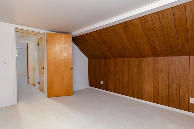 additional living space featuring lofted ceiling, light carpet, and wooden walls