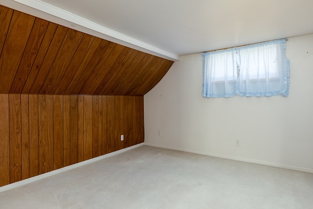 bonus room featuring vaulted ceiling, light colored carpet, and wood walls