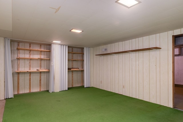 basement featuring carpet and wooden walls