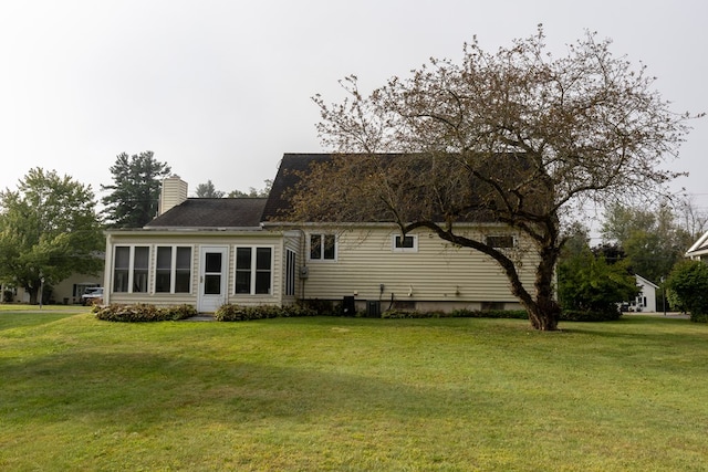 back of property featuring central AC unit and a lawn