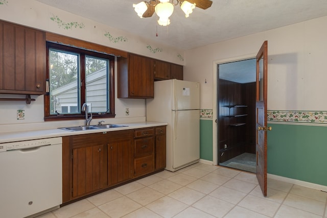 kitchen featuring sink, white appliances, a textured ceiling, and light tile patterned flooring